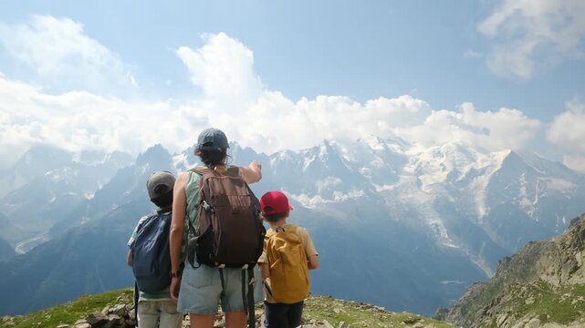 Mother and her two children enjoying a family hiking trip while looking at the majestic mont blanc mountain range from a scenic viewpoint during summer vacation