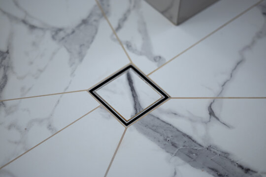 Modern square shower drain on marble bathroom floor tiles