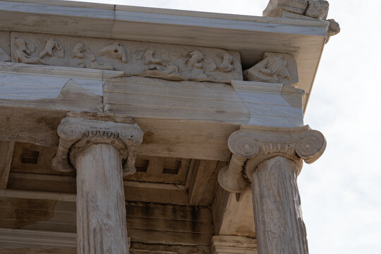 Close-up of ancient Ionic columns and detailed marble frieze at the Propylaea gateway, Acropolis of Athens, Greece.
