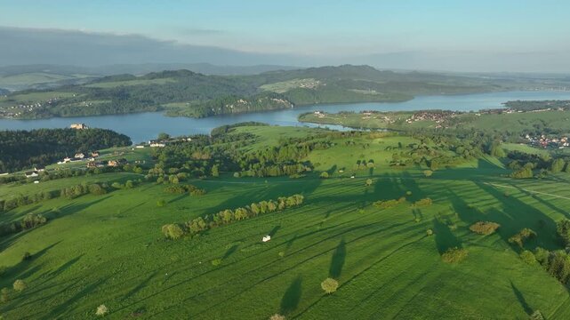 Panoraimc aerial view of Czorsztyn lake and green agricultural fields in spring morning, Pieniny countryside from above