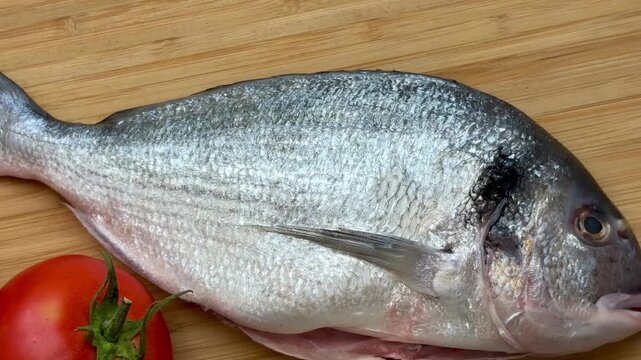 Raw sea bream fish with vegetables. A close-up shot of raw fish, cooking delicious food at home.