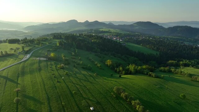 Epic aerial view of rolling green hills and pastures of Pieniny mountains in morning light, springtime nature background