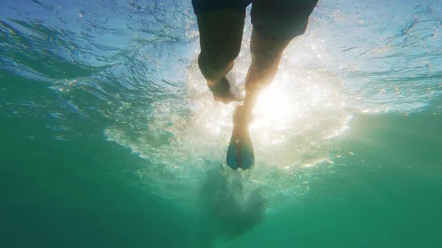 Underwater view of man snorkeling with flippers in clear blue ocean