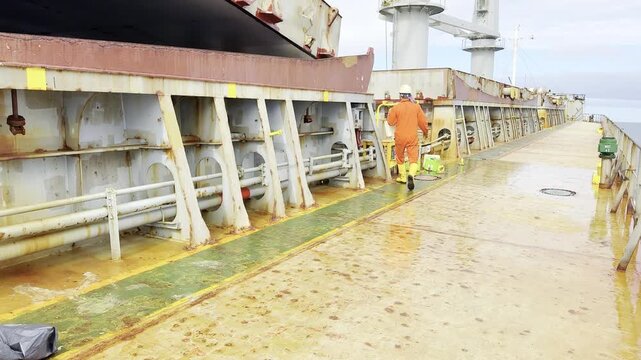 mariner with bucket work on deck of cargo ship