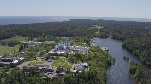 Forward reveal aerial shot of Valaam Monastery and Monastery bay on sunny summer day. Ladoga lake, Karelia, Russia.