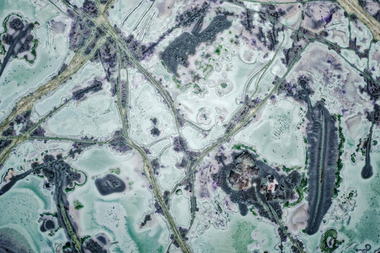 Macro of unique tinguaite rock polished surface from Khibiny forming a microscopic landscape with forest swamp paths and trail patterns, 6 mm field of view