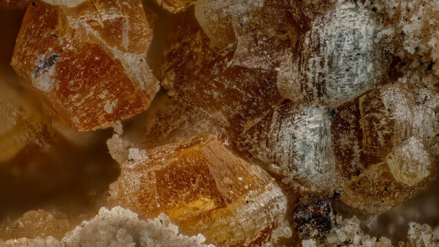 Macro photography of polychrome orange Quintinite crystals texture. Mineral specimen background with zoned crystalline structure from Kovdor