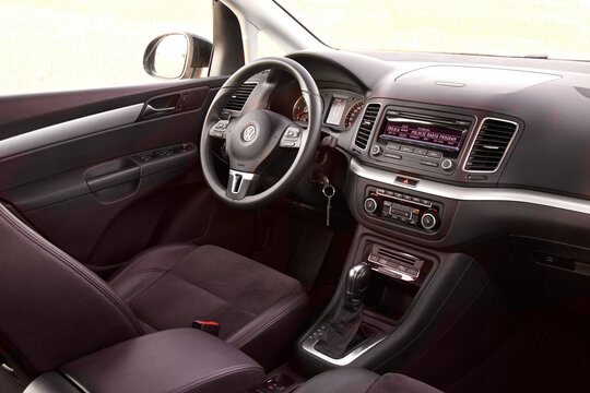The Volkswagen Sharan interior features a dashboard, steering wheel, and gear shift with visible controls and layout, focused on functionality. Zory, Poland 03.07.2015