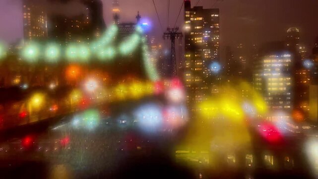 Blurred image of city lights sparkling at night through the window. Travel in a cable car of famous Roosevelt Island Tramway watching the Ed Koch Queensboro Bridge.