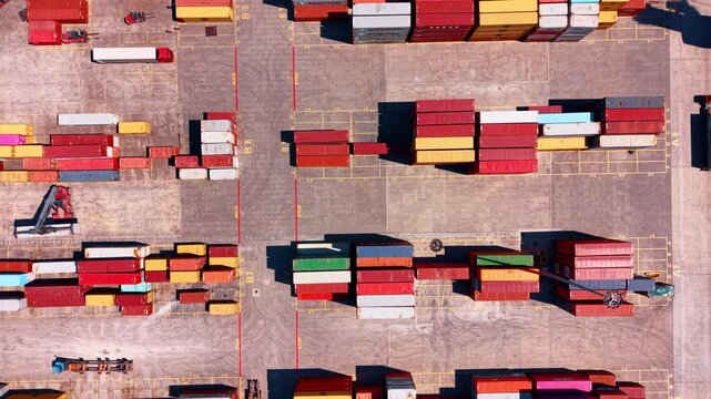 Site with multiple large containers. Machines for transportation of cargo move around. Port facility from top view.