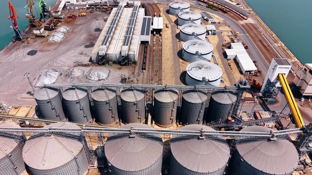 Huge tanks of diverse size at the territory of the modern port. Large maritime facility with railways for world trade and shipping. Aerial view.