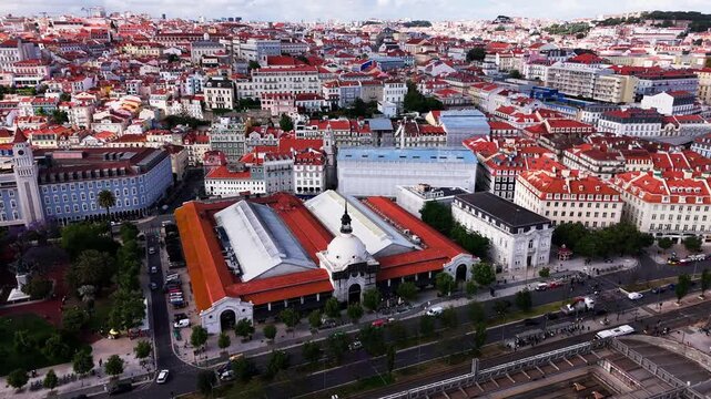 Aerial view of Lisbon cityscape. Timeout Market, railroad paths, red-roofed buildings under cloudy sky