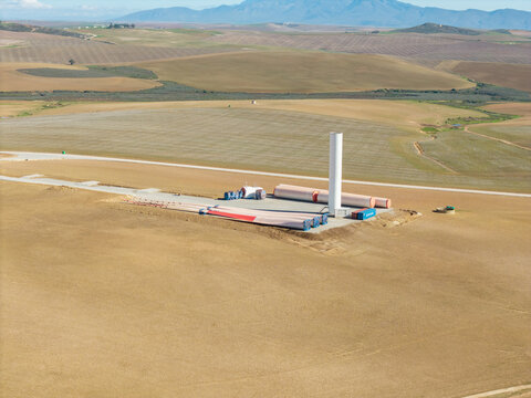 Aerial view of wind turbine components including blades and tower base at a construction site in the rolling hills Swellendam, Western Cape, South Africa.