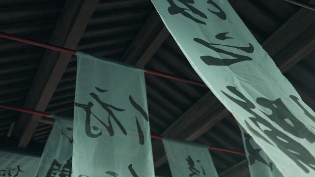 Japanese white fabric banners with calligraphy hanging under wooden eaves