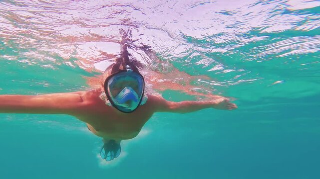 Man in snorkel mask swimming underwater in clear turquoise ocean