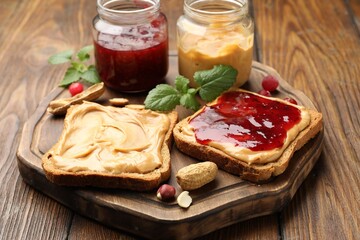 Fototapeta na wymiar Tasty sandwiches with peanut butter, jam, nuts and mint on wooden table, closeup