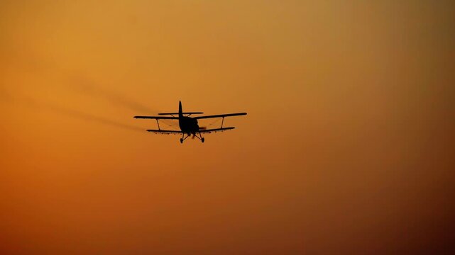 Crop Duster Aircraft Spraying Pesticide at Golden Sunset