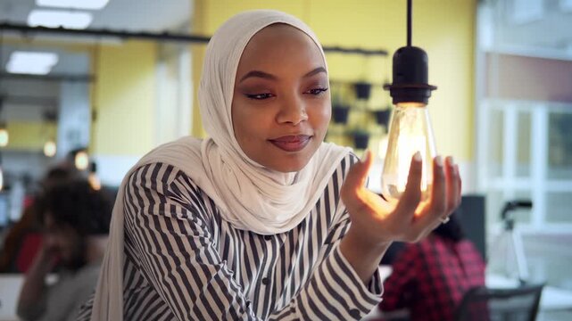 Muslim Businesswoman Holds Glowing Light Bulb for Innovation Idea