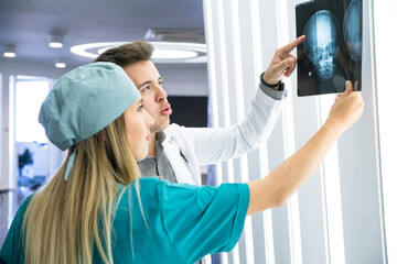 Fototapeta premium Medical professionals discuss a patient's skull X-ray in a hospital radiology department