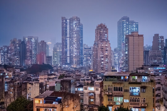 Macau, Maco, China : dense residential towers and illuminated apartment buildings disappearing into humid night haze above the urban skyline of Macau.