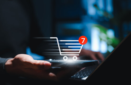 Online shopping cart and e-commerce purchase concept. Person using smartphone and laptop with cart icon, item notification, mobile checkout, digital retail, order process, and online buying experience