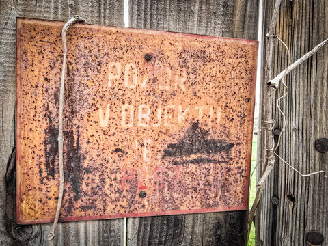 Rusty vintage warning sign in czech on a wooden fence