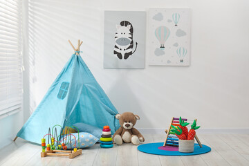 Wigwam, toys and pillows near white wall in child's room © New Africa