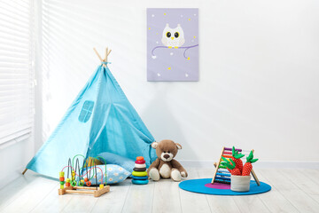 Wigwam, toys and pillows near white wall in child's room © New Africa