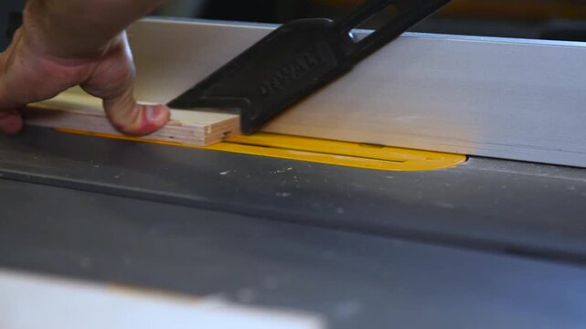 Circular table saw cutting wood in carpenter workshop close up. A running blade on a bench saw sawing trough the wooden log in the middle of a working space, close up footage. A sawing circle that cut