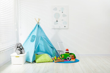 Wigwam, toys and pillows near white wall in child's room, space for text © New Africa