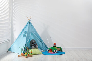 Wigwam, toys and pillows near white wall in child's room, space for text © New Africa