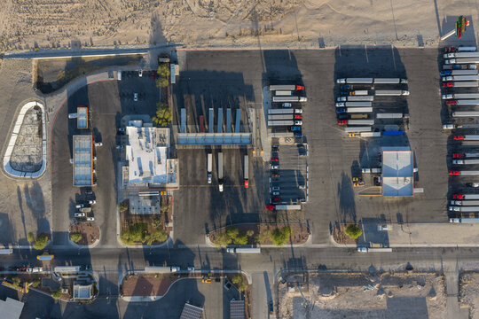 Aerial view of a large truck stop with semi-trucks parked in rows and long shadows cast across the asphalt in Enterprise, Nevada, United States.