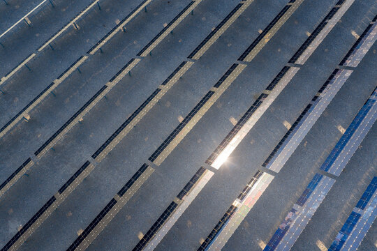 Aerial view of rows of solar panels reflecting bright sunlight in a large renewable energy farm in Enterprise, Nevada, United States.