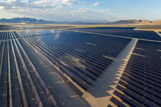 Aerial view of a vast solar panel array stretching across the desert landscape with mountains under a blue sky in Enterprise, Nevada, United States.