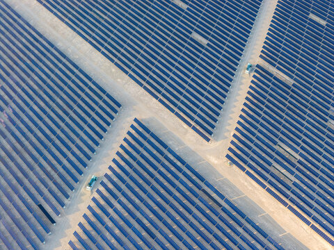 Aerial view of a vast solar farm featuring rows of blue photovoltaic panels and sandy access paths in the desert Enterprise, Nevada, United States.