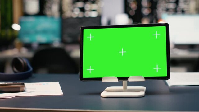 Isolated chroma key screen tablet with empty office space with glass walls offering stunning view of city skyline at night. Workspace with comfortable furniture reflects corporate headquarters.