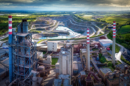 Aerial view of the Irish Cement Ltd facility featuring tall chimneys and a vast open-pit quarry surrounded by green fields in Drogheda, County Louth, Ireland.