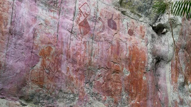 Brightly Colored Pictographs on Stone Wall in Guaviare. The artwork features vivid red hues and intricate patterns.