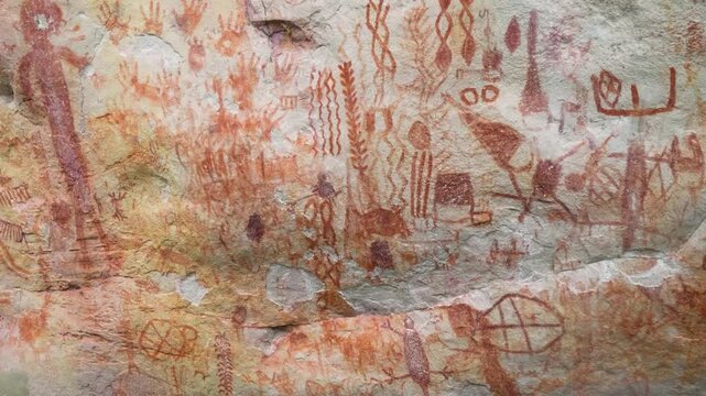 Bright red pictographs showcasing intricate designs and figures on a weathered rock surface.