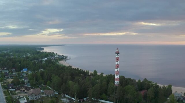 Forward reveal aerial shot of Osinovetsky lighthouse on summer sunrise. Ladozhskoye Osero village, Leningrad Oblast, Russia.