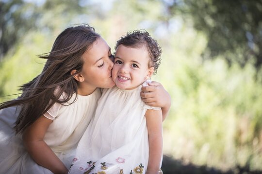 Siblings, big sister gives little sister a kiss