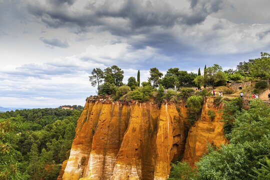 Steep cliffs in the natural park of ochre cliffs with dramatic clouds above, Roussillon, Luberon, Provence, France