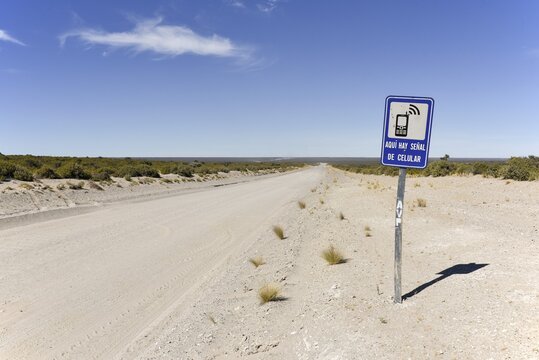 Signpost to a place with mobile phone reception next to endless gravel road, desert of the peninsula Valdes, Patagonia, east coast, Atlantic Ocean, Argentina