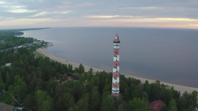 Tilt up aerial shot of Osinovetsky lighthouse on summer sunrise. Ladozhskoye Osero village, Leningrad Oblast, Russia.