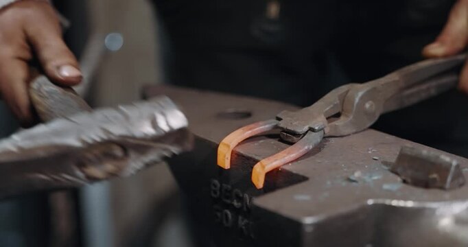 A blacksmith is hammering a horseshoe into a metal anvil in slow motion. Concept of hard work and dedication to the craft