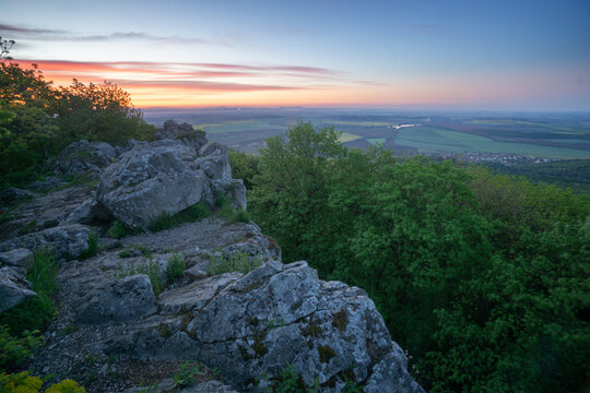 View of Havrania skala in the Male Karpaty mountains with rocky cliffs and lush green forest under a colorful sunset sky Smolenice, Trnava Region, Slovakia.