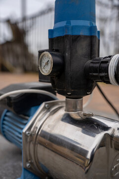 Automatic electronic controller with pressure gauge integrated on a stainless steel water booster pump unit, household or garden pipeline management system hardware.