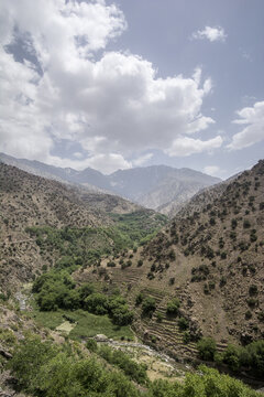 View of the mountain village of Tizi Oussem with terraced fields and rocky slopes under a cloudy sky in the High Atlas Mountains Tizi Oussem, Marrakech-Safi, Morocco.