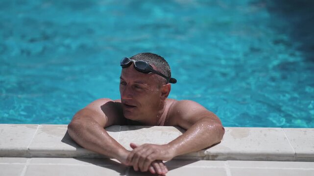 Professional man in a swimsuit is in the water setting swim goggles