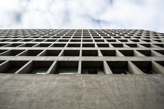 View of the grid-like concrete facade of a modern building in Downtown looking up towards a cloudy sky Lincoln, Nebraska, United States.